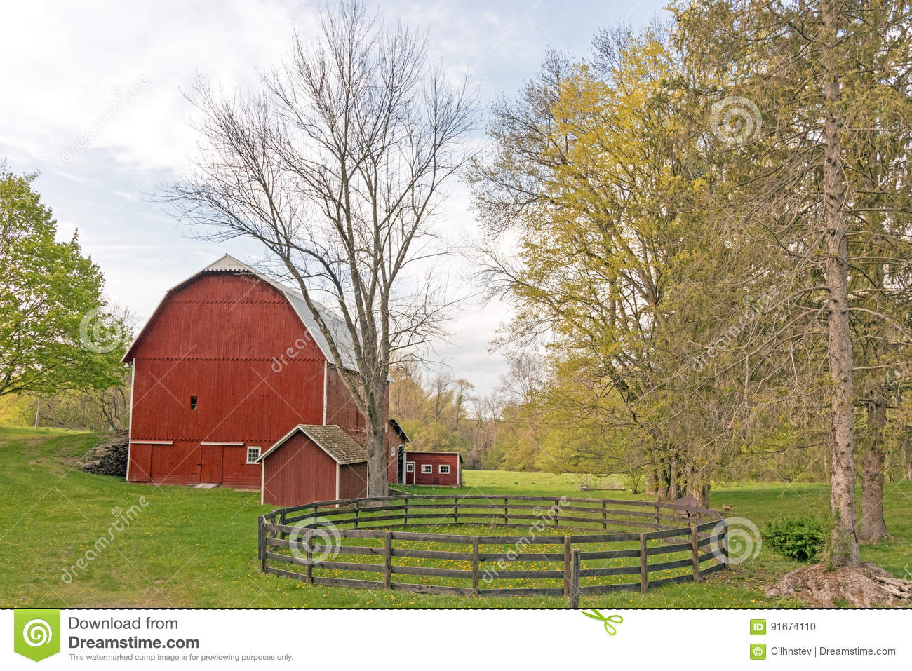A red barn with a circular fenced enclosure out front